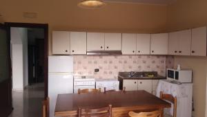 a kitchen with white cabinets and a table with chairs at Edelweiss in Palmi