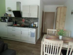 a kitchen with white cabinets and a table and chairs at FeWo am Bogen-Biwak in Groß Wasserburg