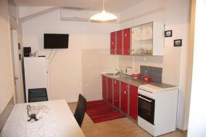 a kitchen with red cabinets and a table and a refrigerator at Apartment in city center in Rijeka