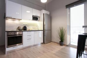 uma cozinha com armários brancos e um frigorífico de aço inoxidável em Walk to Markets from a Cozy Studio em Atenas