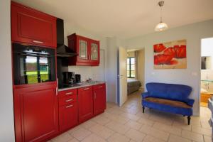 a kitchen with red cabinets and a blue chair at Entre Vignes et Châteaux in Fougères-sur-Bièvre