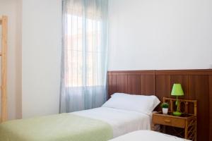 a bedroom with two beds and a window with a green lamp at Apartamentos Calypso in Punta Umbría
