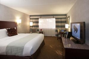 a hotel room with a bed and a flat screen tv at Somerset Inn Troy in Troy