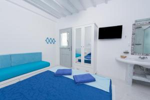 a white room with a blue bed and a sink at Mumua Studios in Mikonos