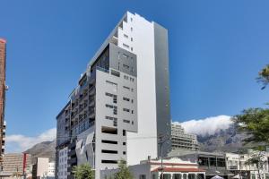 um edifício branco alto com montanhas ao fundo em Backup-Powered Trendy NY City Apartment at Table Mountain em Cidade do Cabo