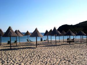 a group of umbrellas on a beach with the ocean at Villa Giuseppina in Villasimius