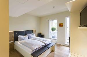 een slaapkamer met een bed met witte lakens en een raam bij Gasthaus Zur Noll in Jena