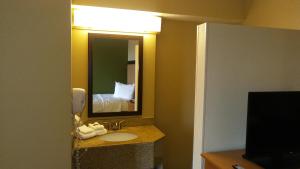 a bathroom with a sink and a mirror and a bed at Extended Stay America Suites - Phoenix - Midtown in Phoenix