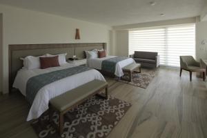 a hotel room with two beds and a chair at Hotel Velvet Plaza in Guadalajara