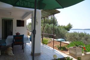 a house with a patio with a green umbrella at Apartmani Surjan in Vela Luka