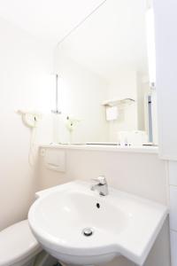 a white bathroom with a sink and a mirror at Hotel inn Grenoble Eybens Parc des Expositions Ex Kyriad in Eybens