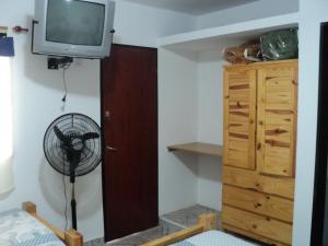 Habitación con ventilador y TV en la pared. en La Nona en Villa Cura Brochero