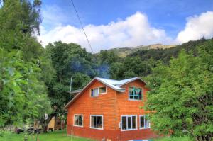 a house in a field with mountains in the background at Turismo Rural Los Alpes in Futaleufú