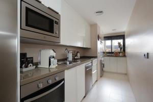 cocina con armarios blancos y microondas en Atico Be suite Granada, en Granada