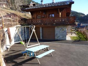 a swing in front of a house with a house at Chalet Le Tredard in Feissons-sur-Salins