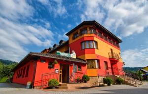 a red and yellow building with a blue sky at Penzión Centrál in Oščadnica