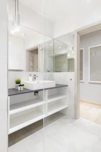a white bathroom with a sink and a mirror at Venezia Apartment in Poznań