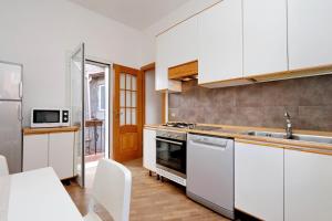 cocina con armarios blancos, fregadero y mesa en Bella Trastevere, en Roma