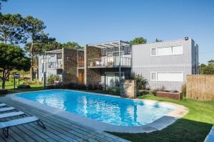 a swimming pool in front of a house at Entre Pinos Eco Box Apart in Punta del Este