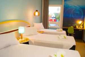 um quarto de hotel com duas camas e uma janela em Delphin Surf Hotel no Guarujá