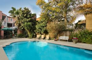 a blue swimming pool with a bench and trees at Lamothe House Hotel a French Quarter Guest Houses Property in New Orleans