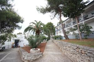 a walkway in front of a building with palm trees at Hotel Sali in Sali