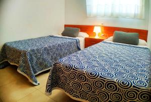 a bedroom with two beds with blue and white sheets at desolyplaya Colomeras 2J in Oropesa del Mar +70 photos