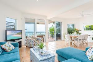 a living room with a blue couch and a tv at Moreton Bay Beach Lodge in Cleveland