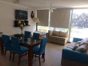 sala de estar con mesa y sillas azules en Departamento Papudo Laguna, vista estero y mar, en Papudo