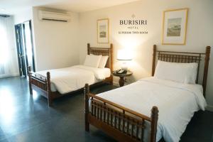 Buri Siri Boutique Hotel في شيانغ ماي: سريرين مع شراشف بيضاء في الغرفة