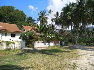 uma casa ao lado de uma estrada com palmeiras em Beach house em Praia de Taling Ngam