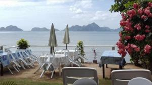 a group of chairs and tables and umbrellas near the water at Desert Rose Hotel in El Nido
