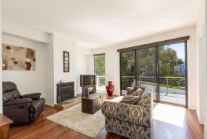 a living room with a couch and a tv at STYLISH, SUN-DRENCHED AND SOPHISTICATED in Inverloch