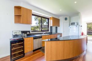 a kitchen with wooden cabinets and a counter top at STYLISH, SUN-DRENCHED AND SOPHISTICATED in Inverloch