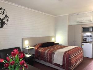 a bedroom with a bed and a couch and a table at Goulburn Motor Inn in Goulburn