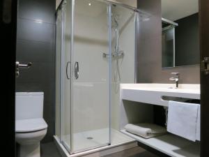 a white toilet sitting next to a shower in a bathroom at Apartamentos Clarín in Oviedo