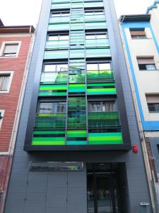 a green double decker bus parked in front of a building at Apartamentos Clarín in Oviedo