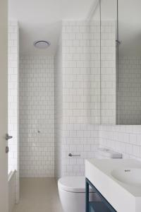 a white bathroom with a toilet and a sink at Swainson on Castle in Adelaide