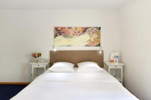 a bedroom with a bed with two tables and a painting at Hotel Hirschen in Zürich