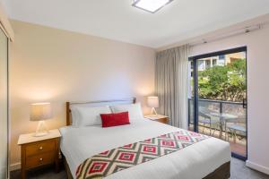 a bedroom with a large bed and a balcony at Nesuto Mounts Bay in Perth