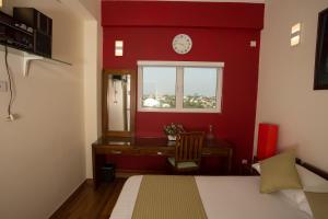 a bedroom with a red wall with a desk and a window at Shalom Residence Nawala in Colombo