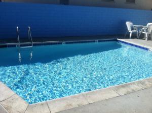 a swimming pool with chairs and a blue wall at Jolly Roger Hotel in Los Angeles