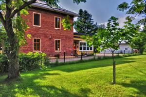 a red brick house with a tree in the yard at Gîte TerreCiel in Baie-Saint-Paul