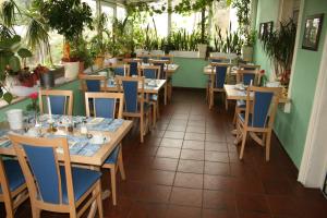 une salle à manger avec des tables, des chaises et des plantes dans l'établissement Hotel am Schloss Borbeck, à Essen