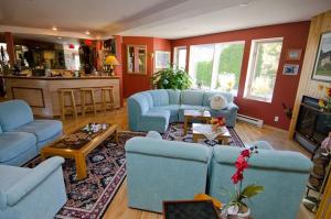 a living room with blue couches and a kitchen at Auberge du Jardin in Petit-Saguenay