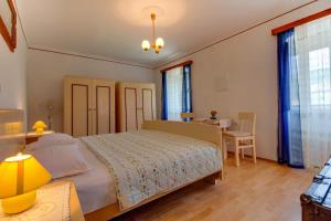 a bedroom with a bed and a desk and windows at Apartman Corino in Veli Lošinj