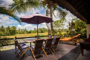 a table with chairs and an umbrella on a deck at Lodtunduh Sari in Ubud