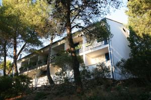 a white house with a balcony in the woods at Hotel Sali in Sali