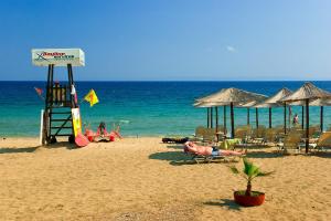 a person laying on a beach with chairs and umbrellas at Sermilie Beach Houses in Psakoudia