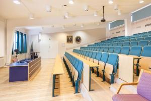 une salle de conférence vide avec des chaises bleues et un podium dans l'établissement Lepaan Kartanon Toimela, à Lepaa